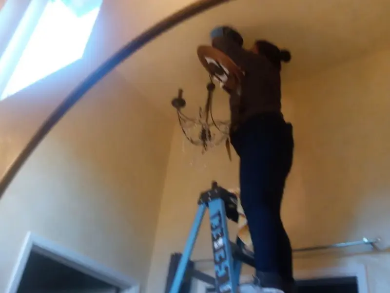 Electrician installing a chandelier in a Boca Raton residence